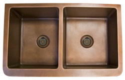 Double bowl copper farmer sink with stylized flower motif