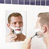 Man shaving with fog-free shower mirror